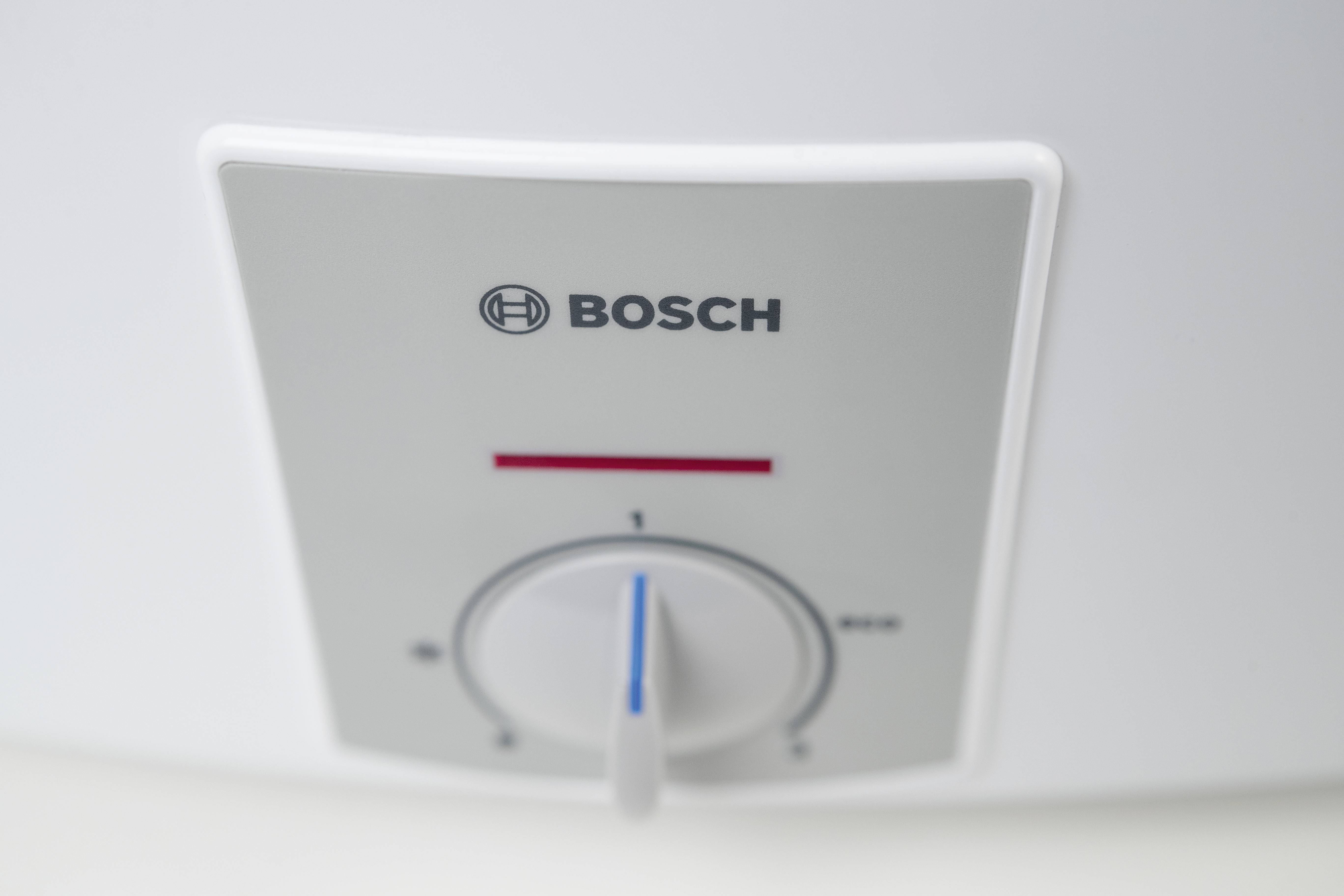 Bílý Bosch panel s regulátorem teploty. Regulátor je nastaven na střední pozici, logo Bosch je viditelné nahoře.