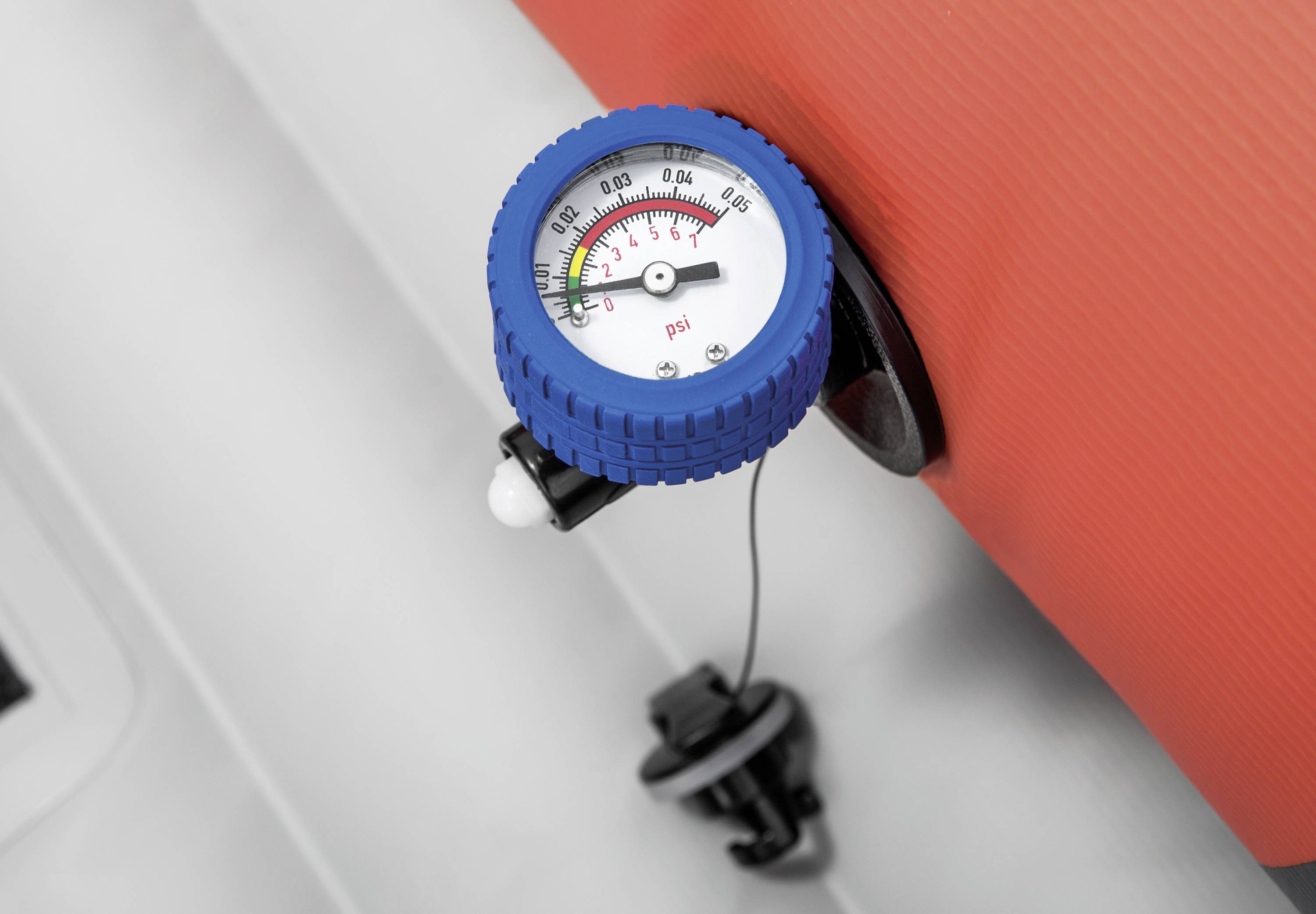Detailní záběr tlakoměru na nafouklém červeném nafukovacím člunu, který ukazuje 0,25 psi, což je pod bezpečnostní hranicí.