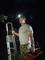 Muž v maskáčových kalhotách a tričku drží žebřík a montážní kufřík, na hlavě má čepici s čelovkou a stojí ve tmě.