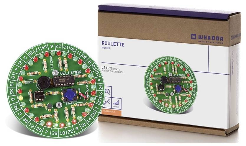 Sada elektronické rulety od Vellemanu pro výuku elektroniky, kulatá deska plošných spojů s LED diodami a komponenty, zobrazená před obalen.