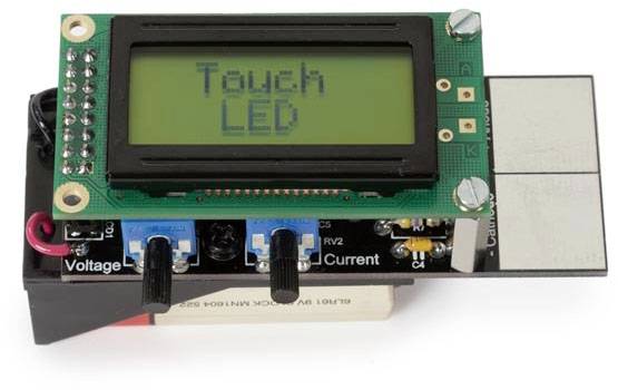 Elektronický modul s LCD displejem zobrazujícím 'Touch LED'. Pod ním jsou ovladače s označeními pro napětí a proud.
