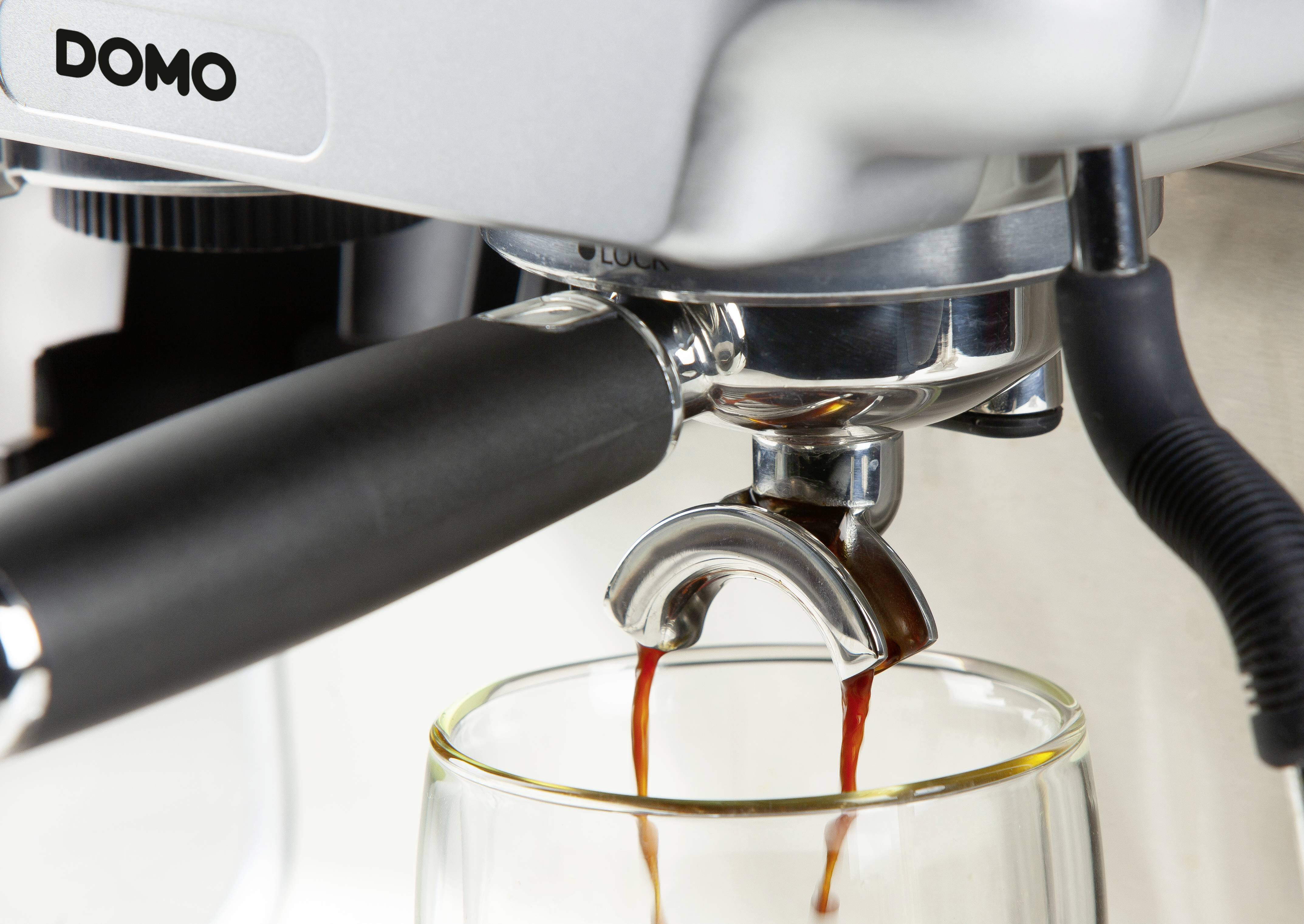 Detailní záběr kávovaru, jak nalévá espresso do sklenice umístěné pod ním.