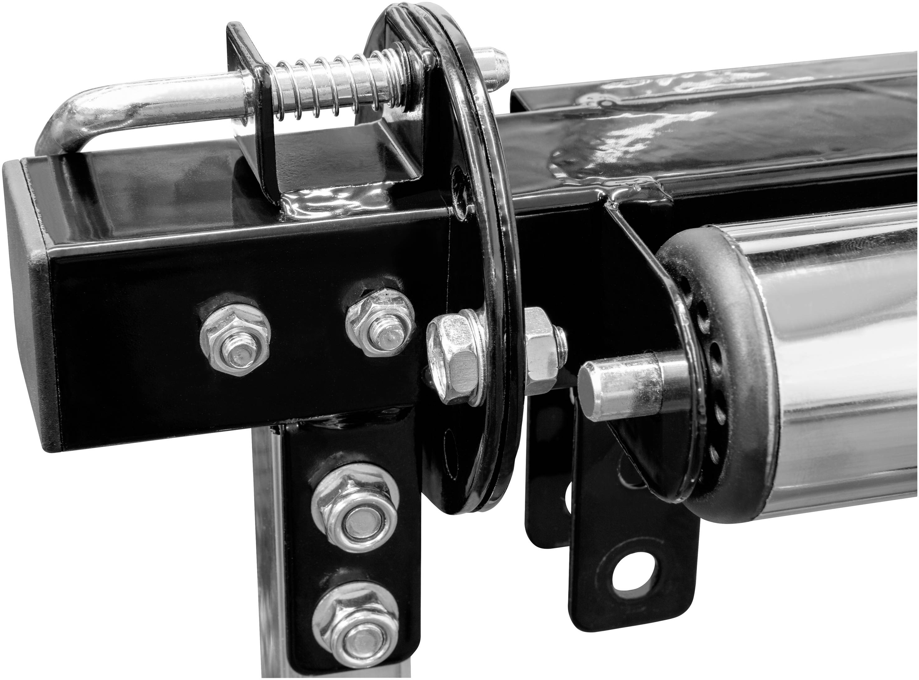 Detailní záběr kovového kování s čepy a pružinami, pravděpodobně součást mechanického zařízení nebo vozidla, bez rozpoznatelných označení.