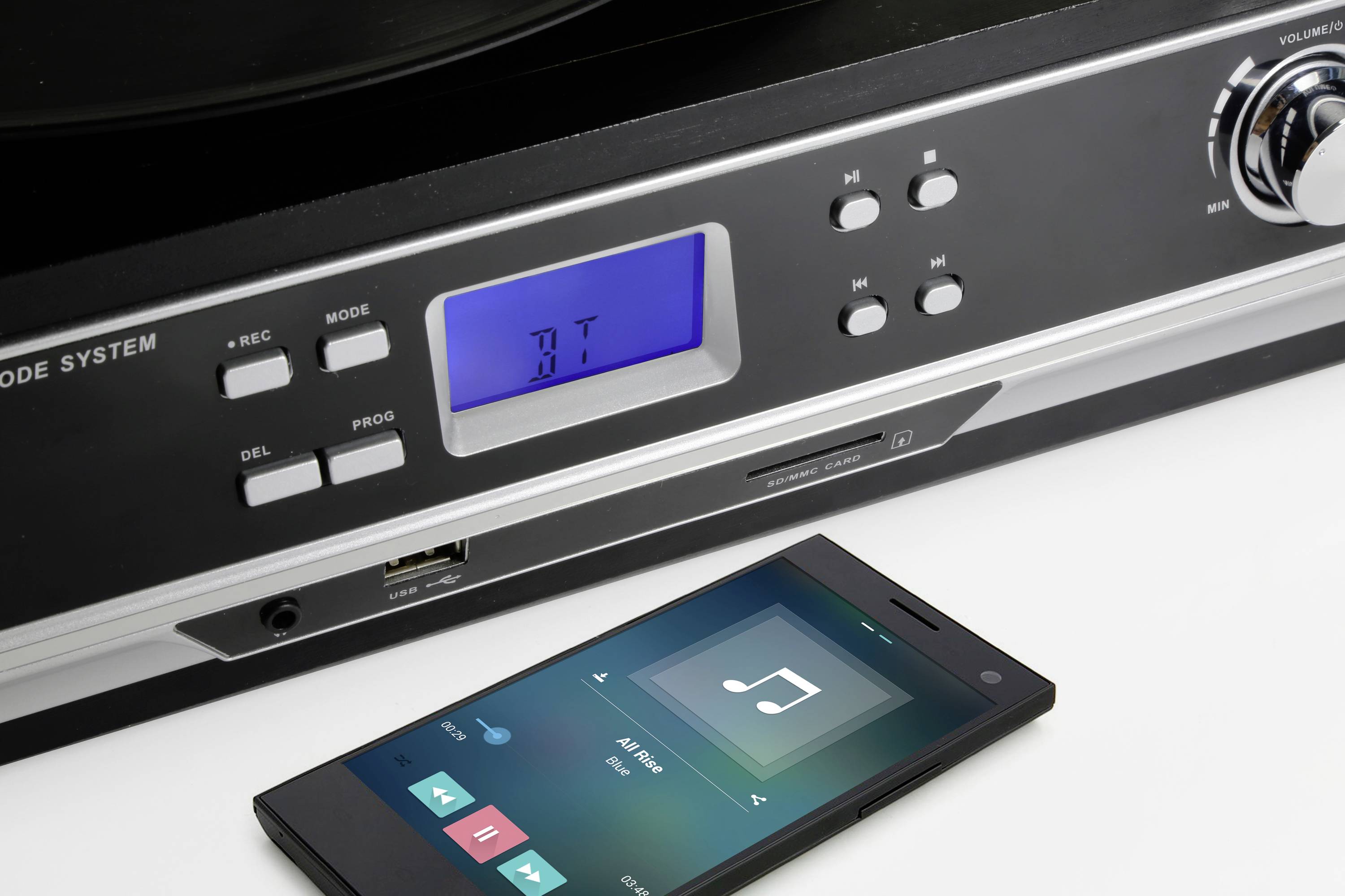 Smartphone přehrává hudbu před stereo systémem. Stereo systém s modrou LED indikací zobrazuje 'bt' pro připojení Bluetooth.