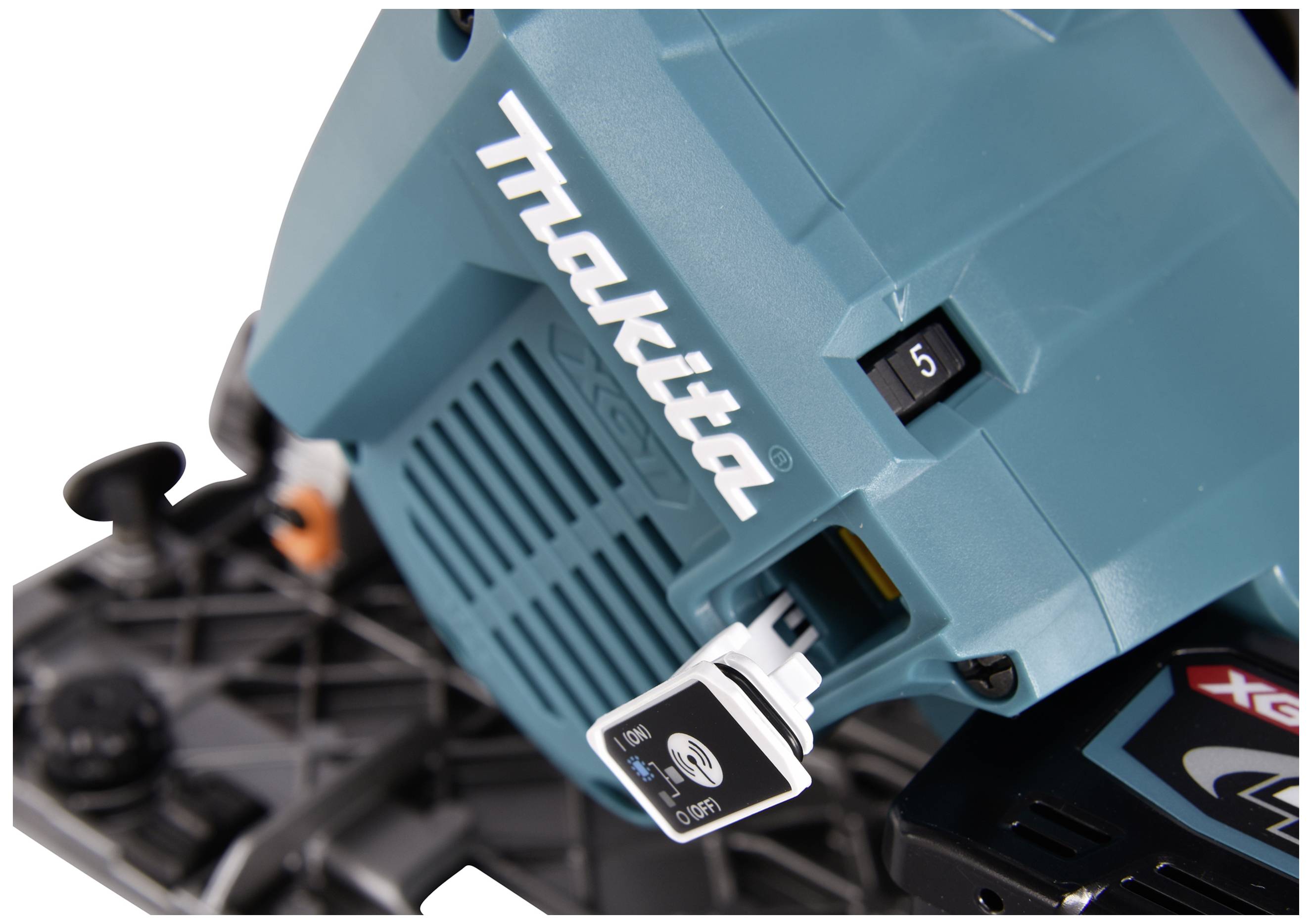 Detailní záběr zelené elektrické strojní části s logem Makita. Je viditelný přepínač s čísly 5 a 6.