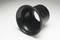 Černý, trychtýřovitý objekt na světlém povrchu, pravděpodobně součást optického přístroje nebo technického zařízení.