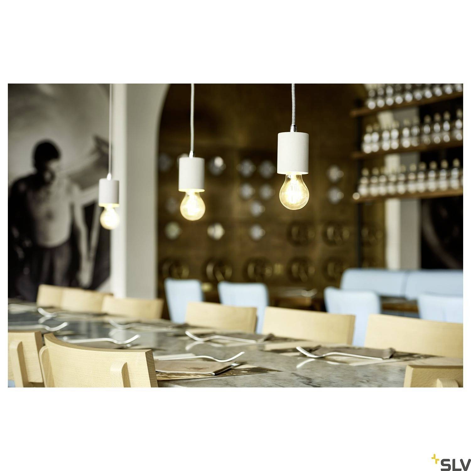 Elegantní restaurační interiér s řadou závěsných lamp nad stolem prostřeným pro hosty a s modrými židlemi v pozadí.