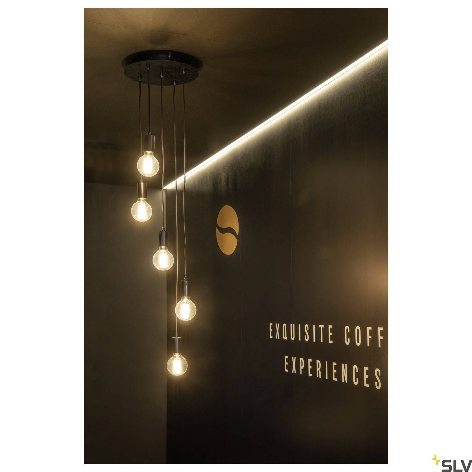 Závěsné lampy se zářícími žárovkami visí ze stropu. V pozadí je vidět cedule s nápisem 'Exquisite Coffee Experiences'.