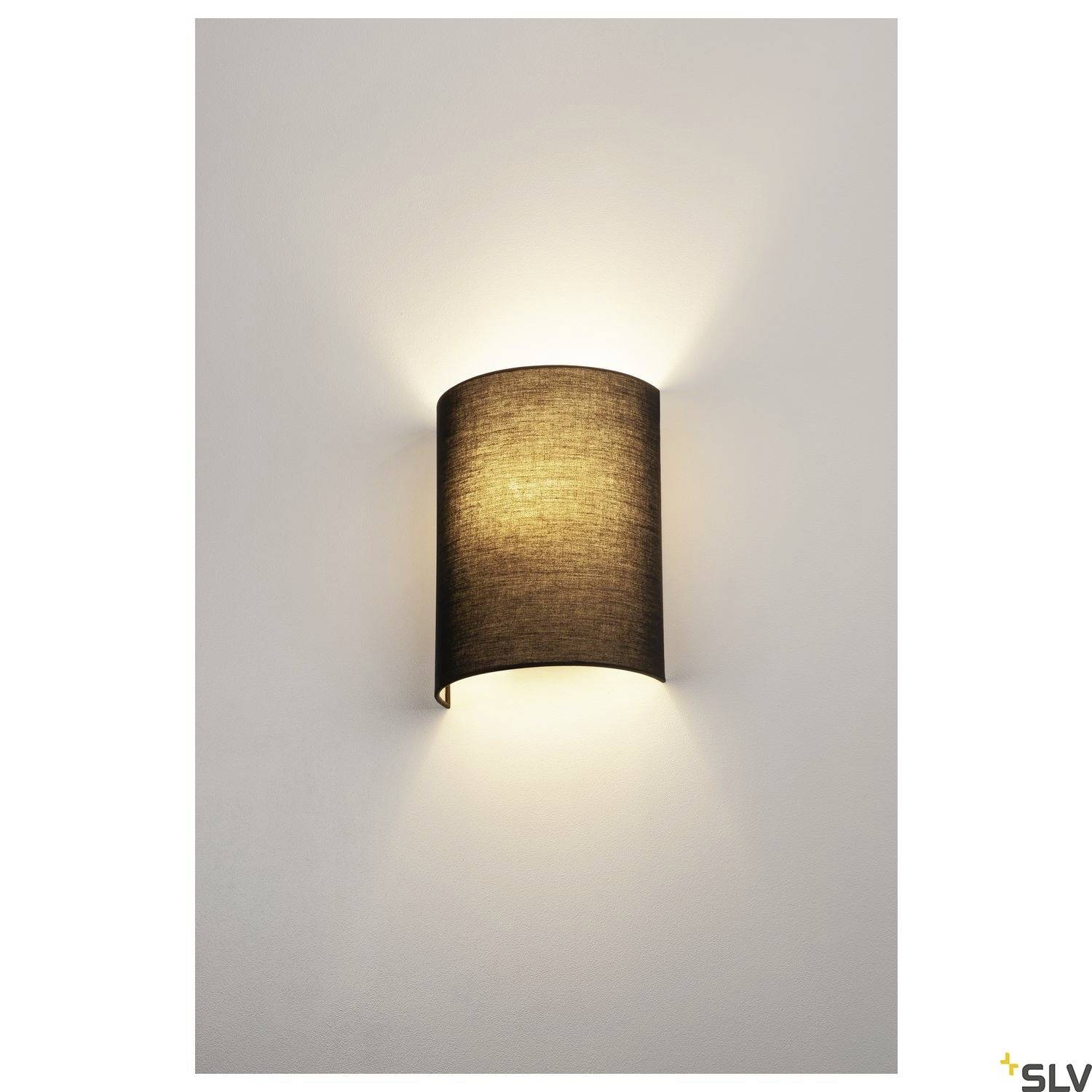Nástěnná lampa s textilním stínidlem vyzařuje teplé světlo do okolí a vytváří útulnou atmosféru.