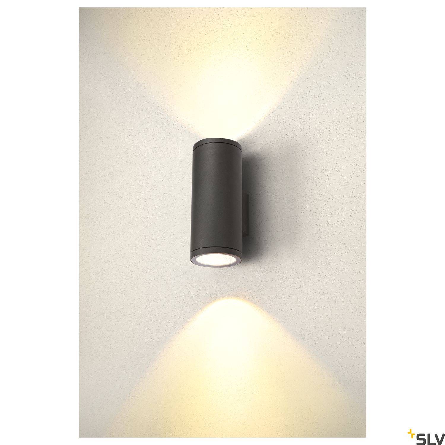 Černá nástěnná lampa vyzařuje světlo nahoru a dolů na stěnu.