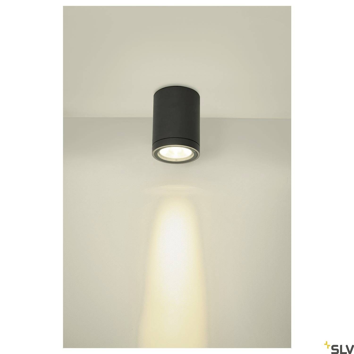 Stropní svítidlo válcovitého tvaru vrhá dolů jasný světelný kužel. Svítidlo je černé a má moderní design.