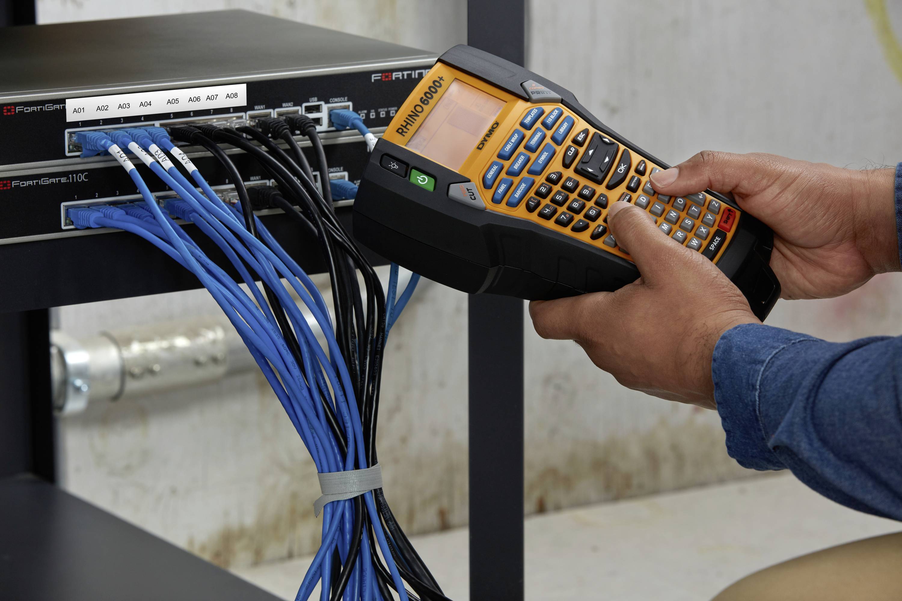 Jedna osoba používá přenosné měřicí zařízení ke kontrole kabelů na síťovém switchi namontovaném na regálu.