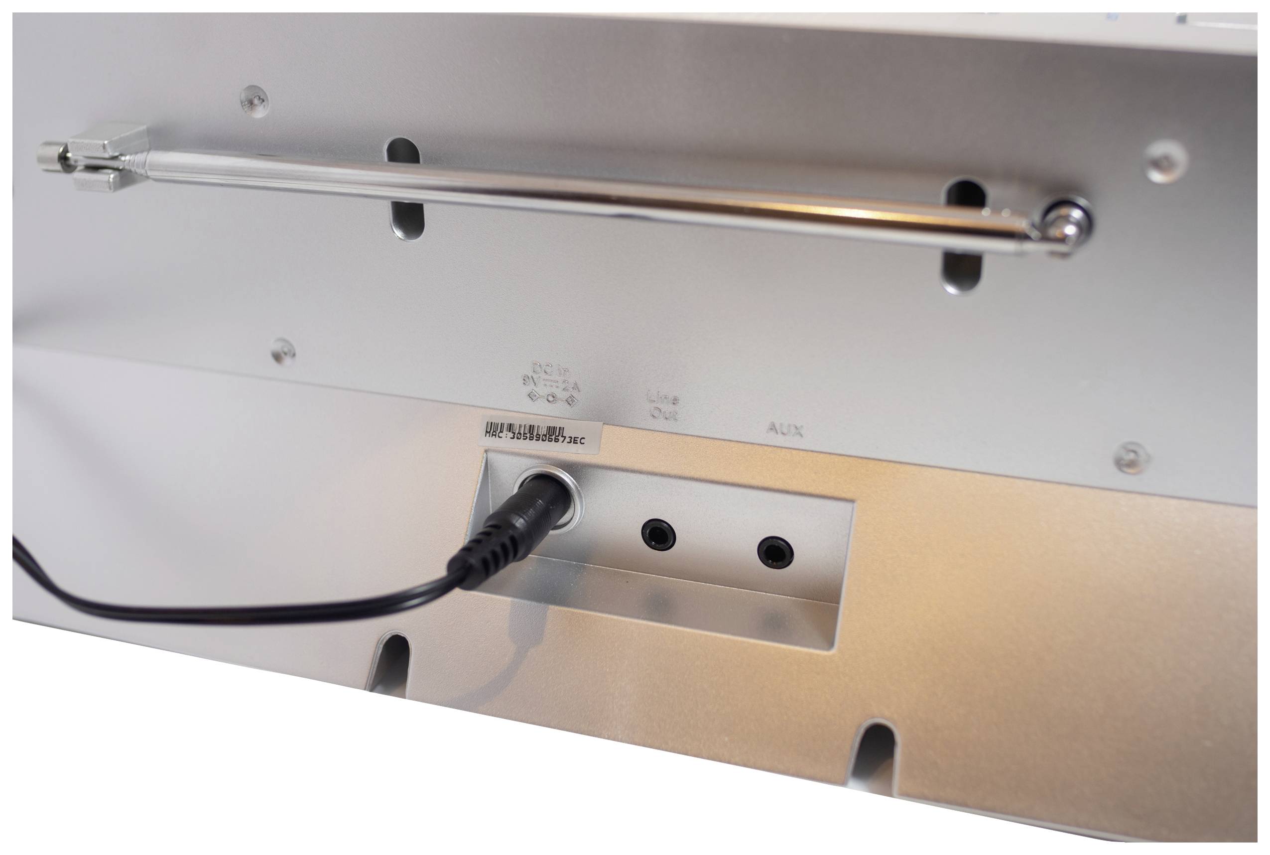 Zadní strana elektronického zařízení s několika porty, včetně síťového konektoru se zapojenou zástrčkou.