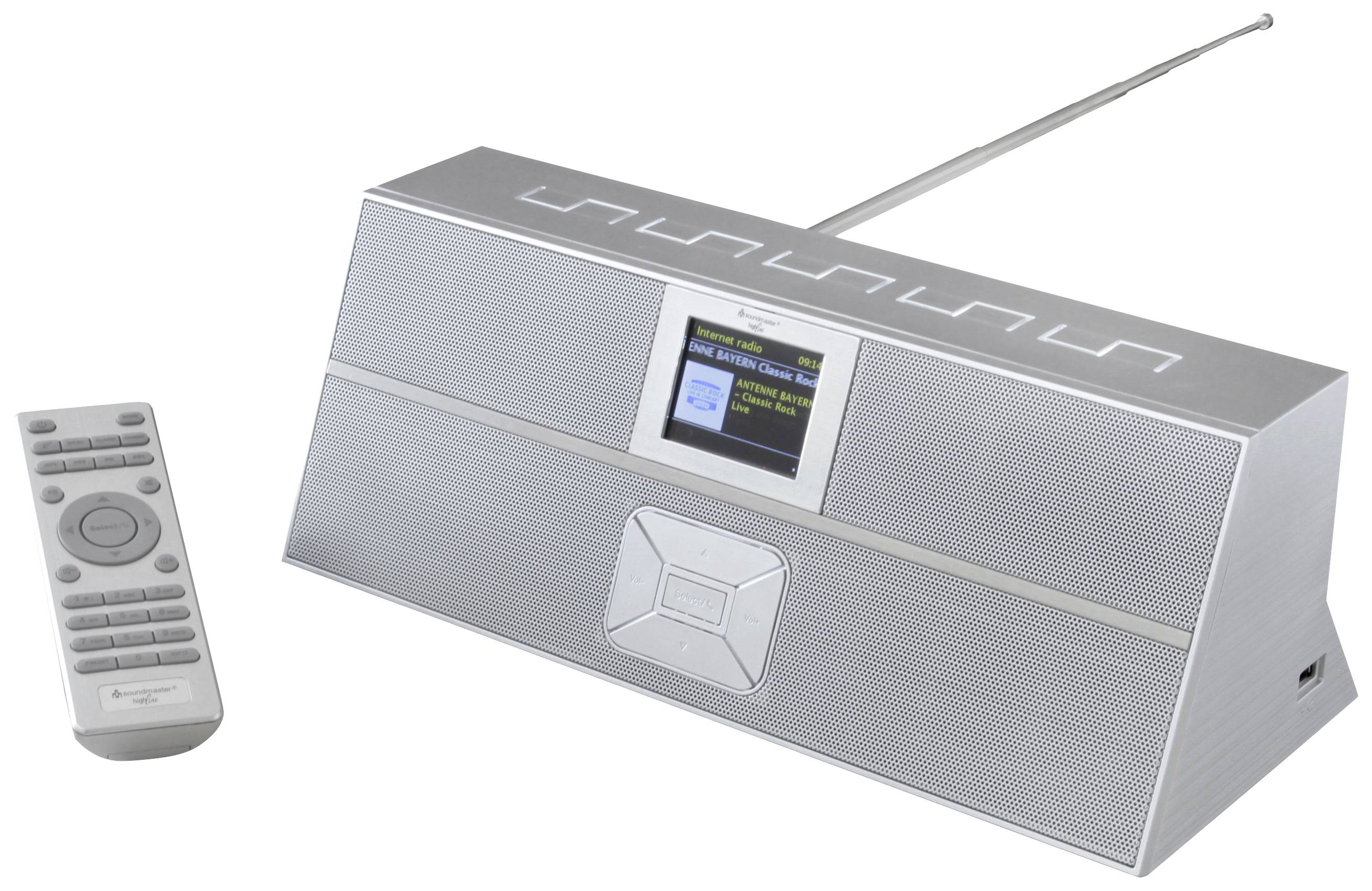 Stříbrné rádio s výsuvnou anténou a malou obrazovkou. Vedle něj leží dálkový ovladač.