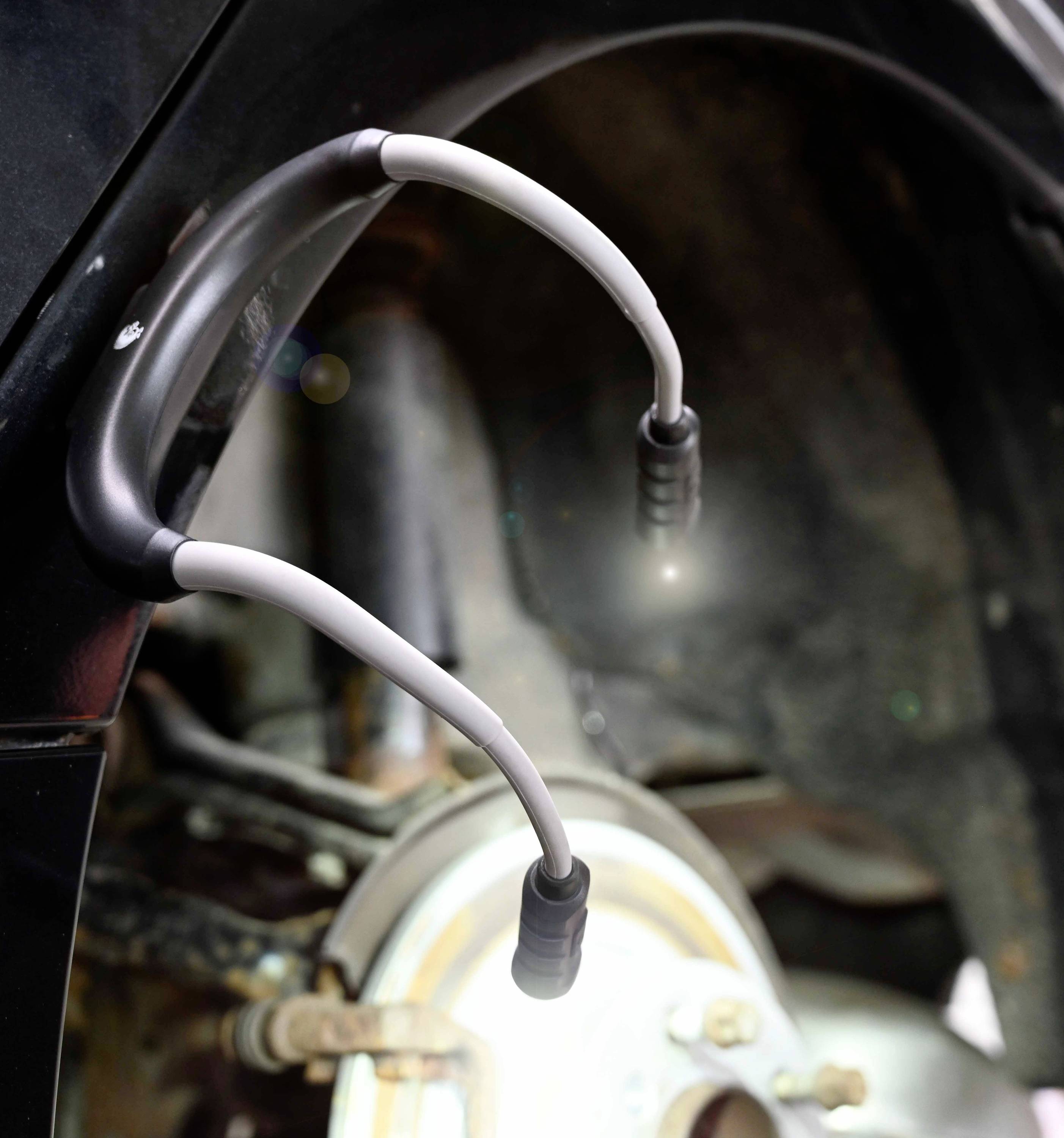 Detailní záběr pneumatiky automobilu s elektrickou nabíjecí jednotkou připojenou k brzdovému třmenu.