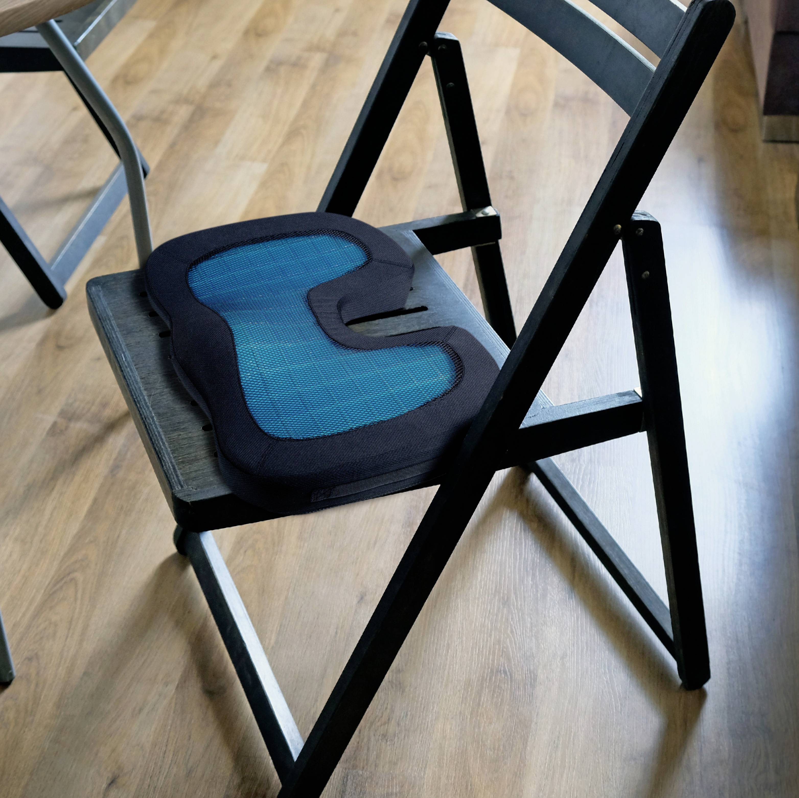 Skládací židle s modrým sedákem stojí na dřevěné podlaze. Židle je mírně natočená směrem ke kameře.