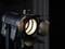 Černý studiový reflektor s otevřenými klapkami vrhá jasné světlo a osvětluje prostor před tmavým pozadím.