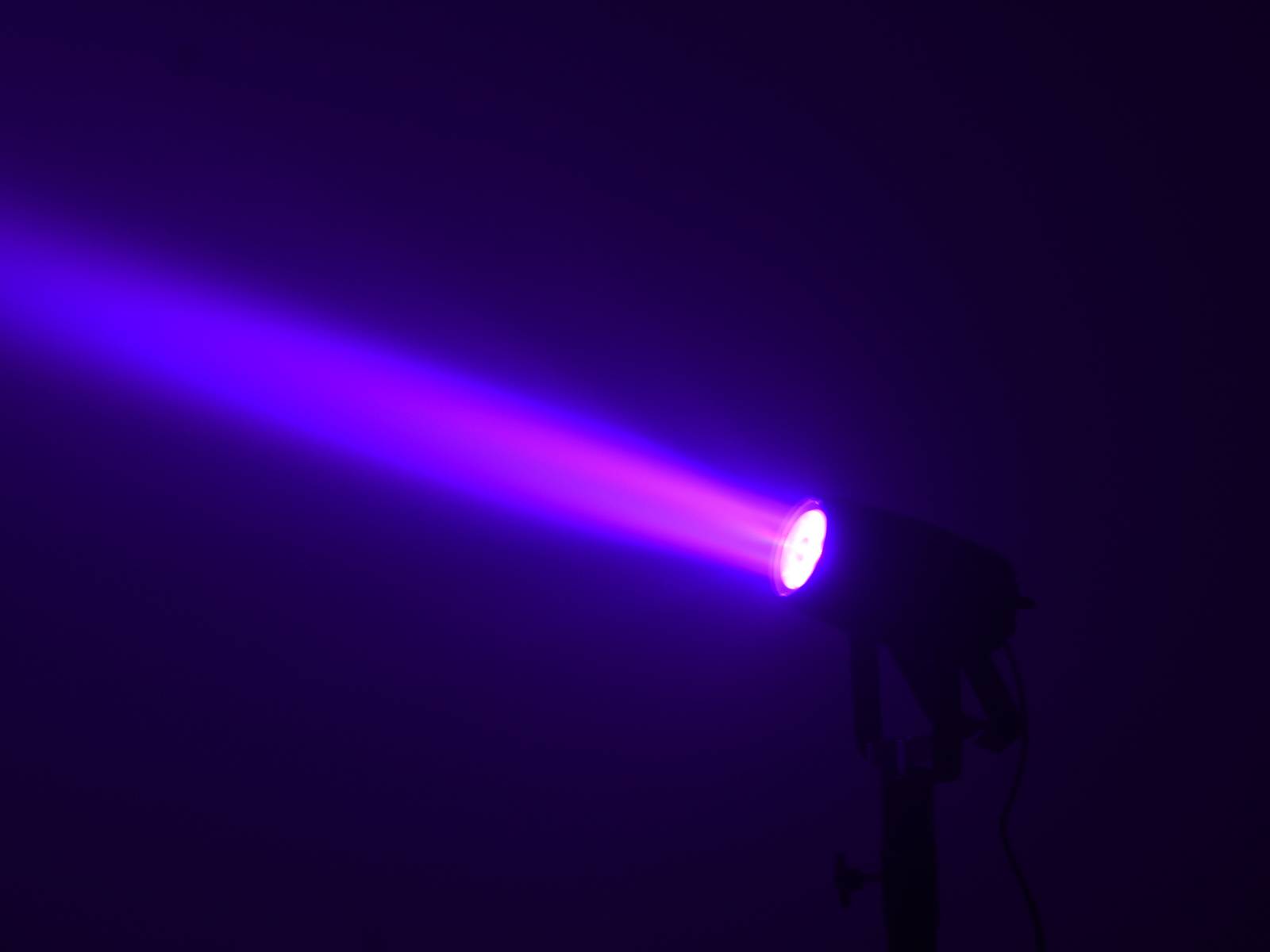 Reflektor promítá fialovo-modrý světelný paprsek v tmavé místnosti.
