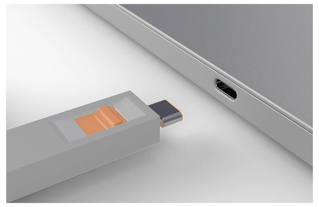 USB flash drive je vkládán do bočního portu notebooku s viditelným oranžovým jezdcem na jednotce.