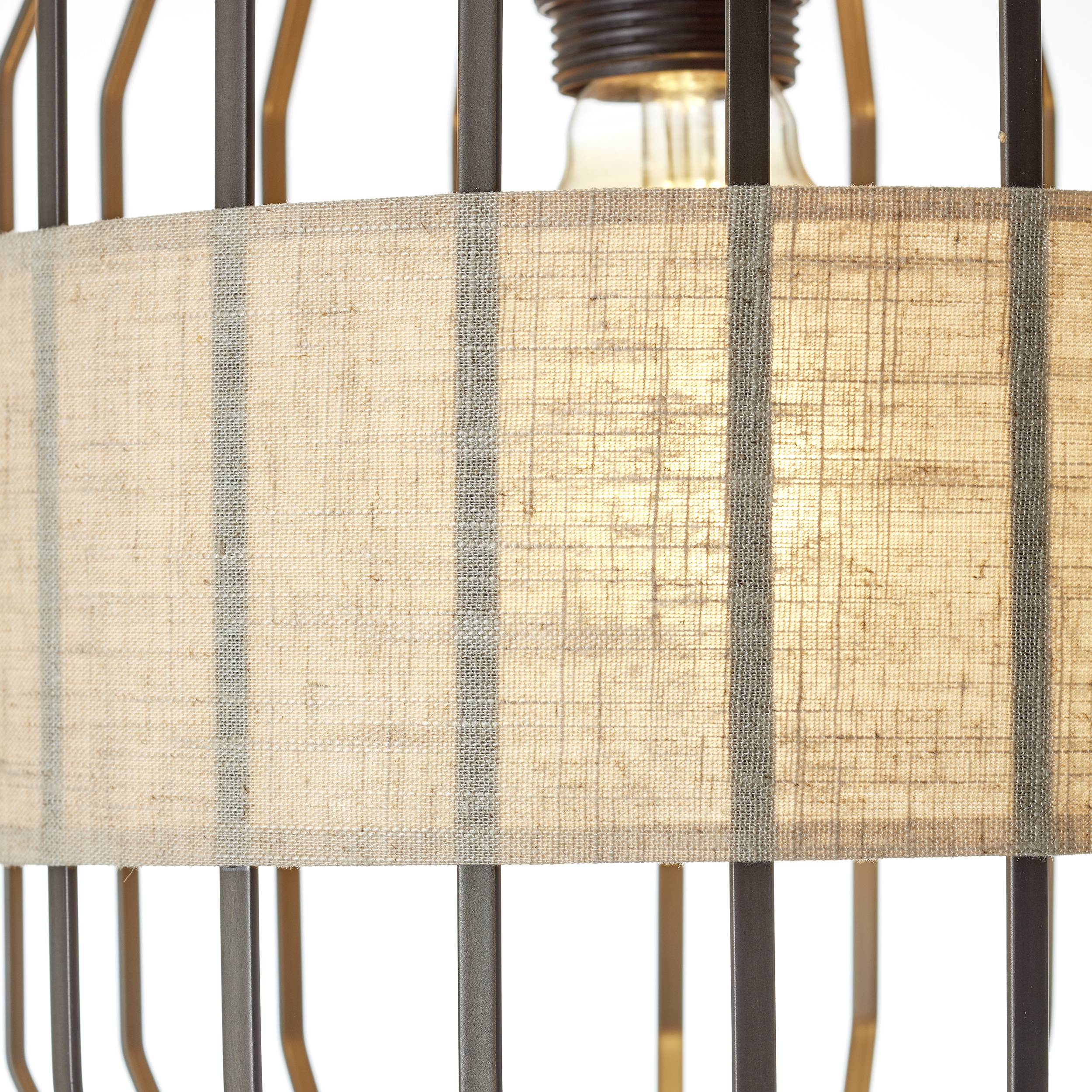 Lampa s textilním stínidlem v geometrickém kovovém rámu, jemně svítící.