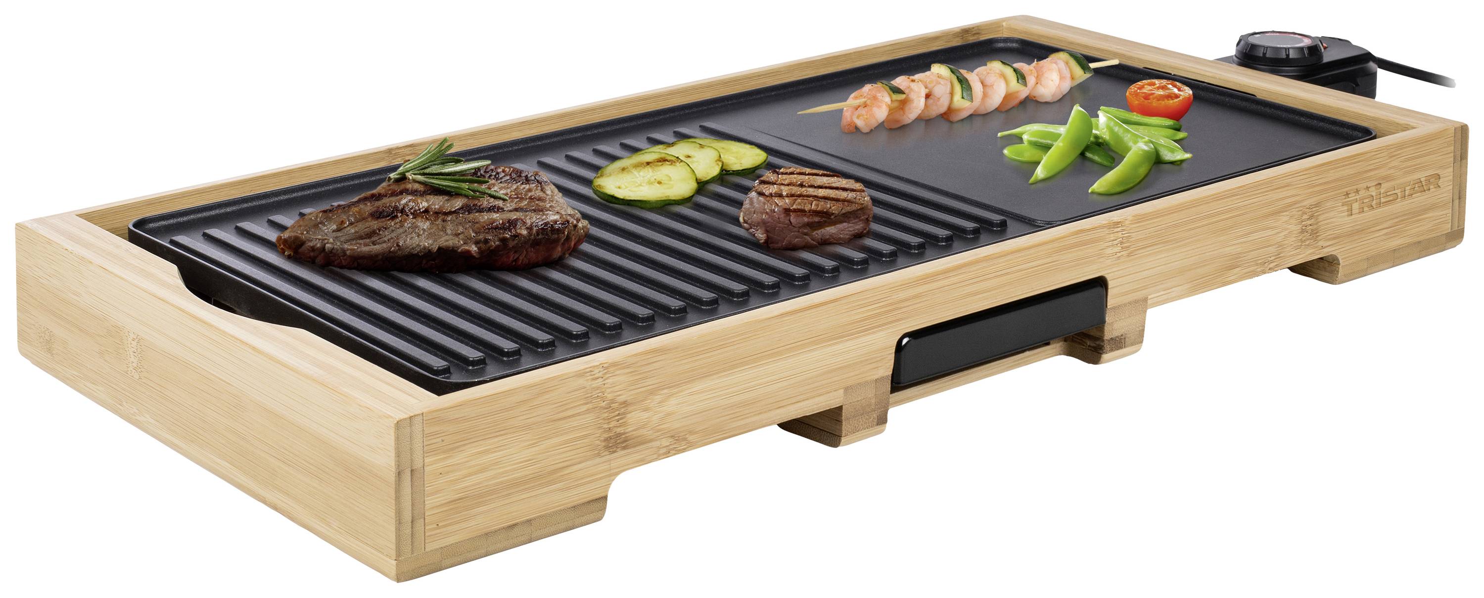 Elektrický stolní gril s bambusovým rámem. Na grilovací ploše leží steak, cuketa, krevetový špíz, rajče a fazole.
