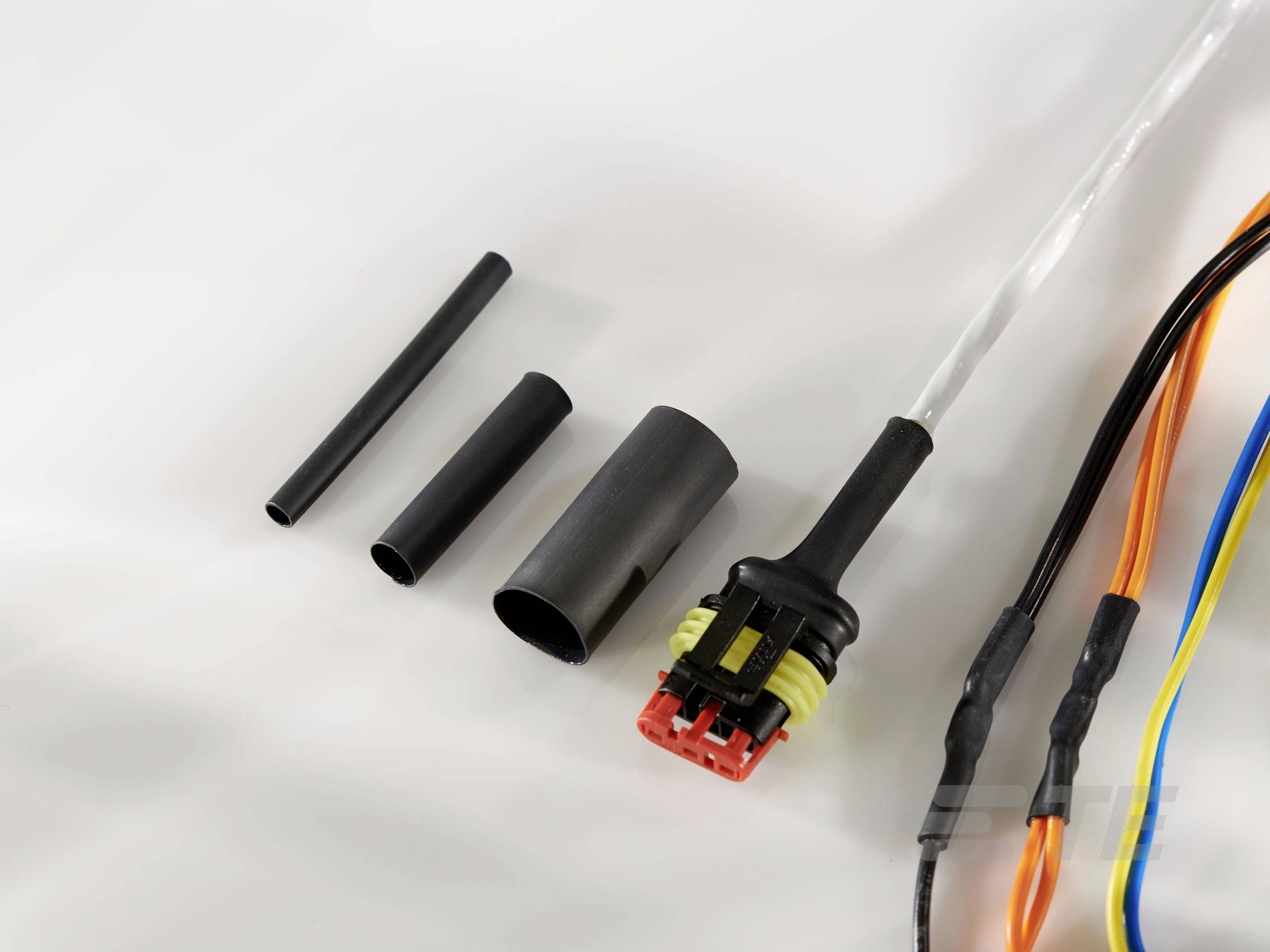 Elektrické kabely s teplem smrštitelnými trubicemi a zástrčkou zobrazené na bílém pozadí.
