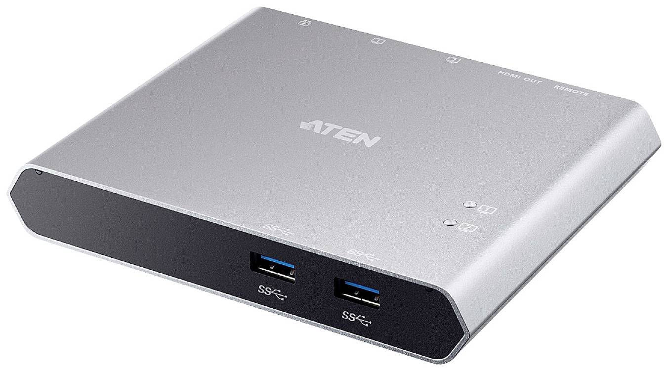 Stříbrné, obdélníkové zařízení se dvěma USB porty na přední straně a několika dalšími konektory nahoře, pravděpodobně rozbočovač nebo switch.