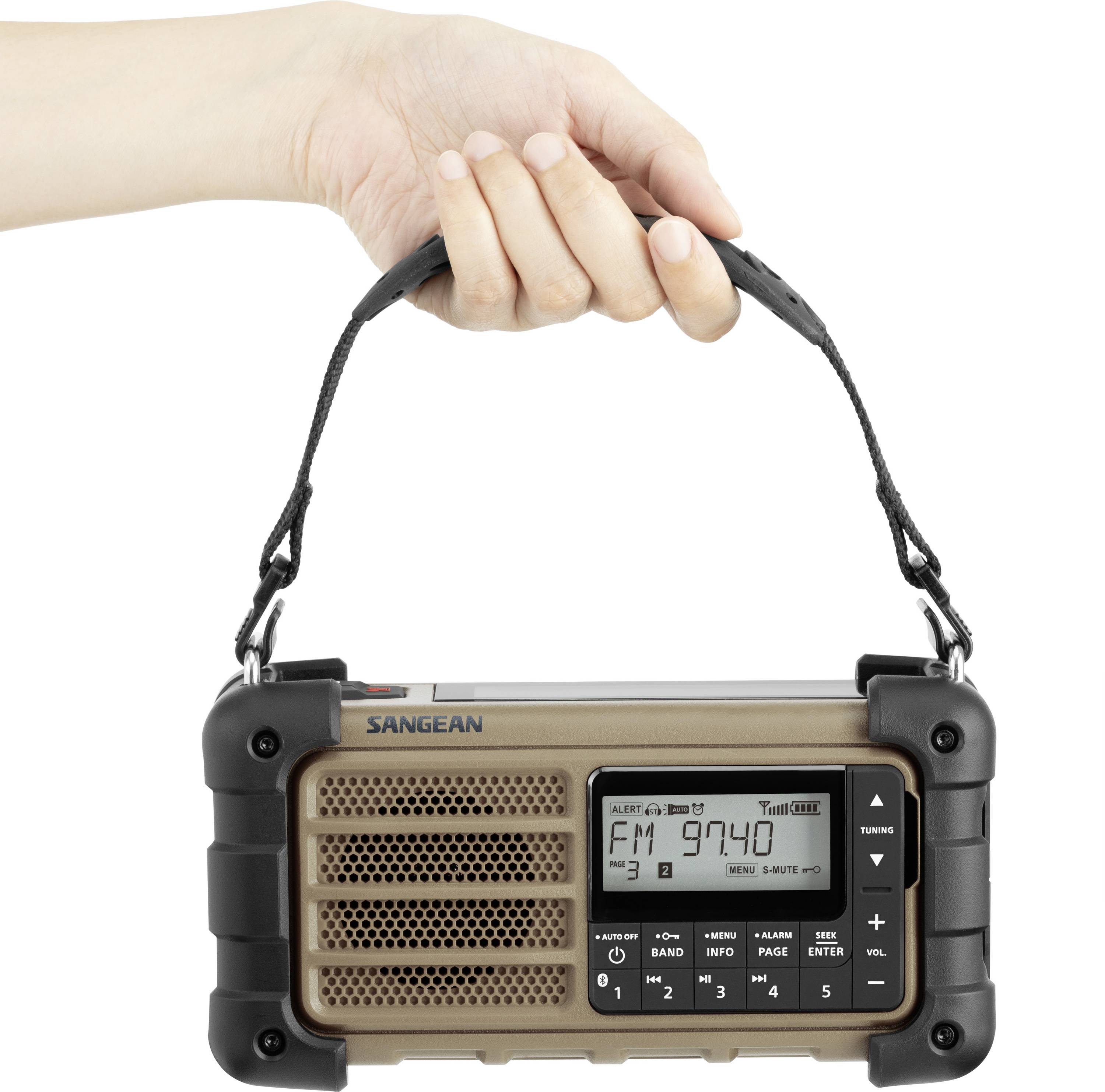 Jedna ruka drží přenosné rádio s displejem, který zobrazuje 'FM 97.40'. Rádio má ovládací tlačítka a robustní design.