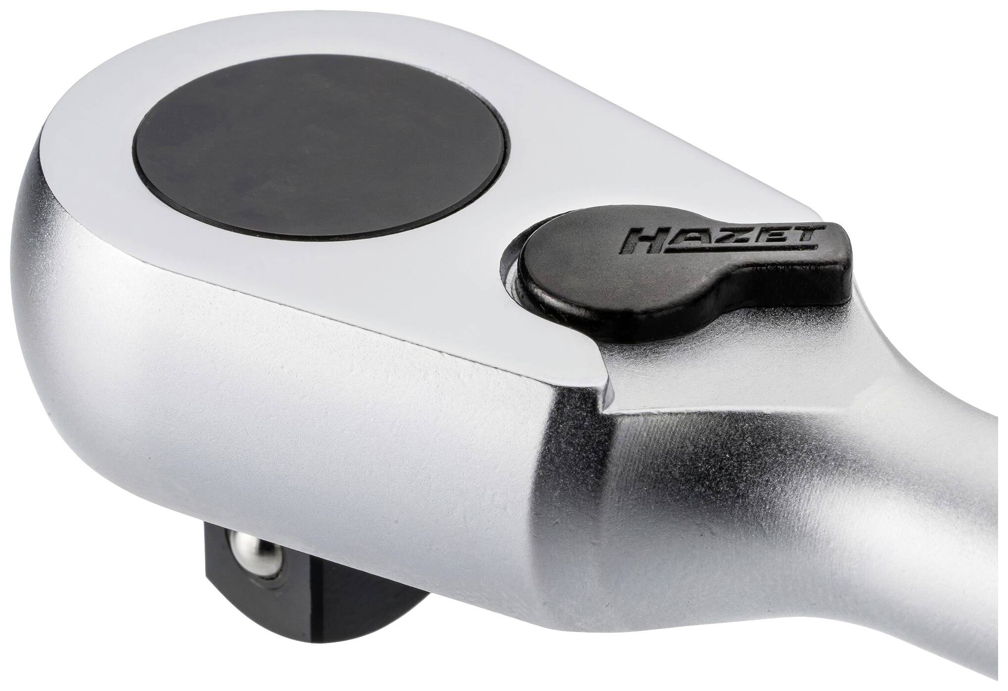 Chromovaná otočná hlavice ráčny s černým kulatým přepínačem, na němž je napsán název značky 'Hazet'.
