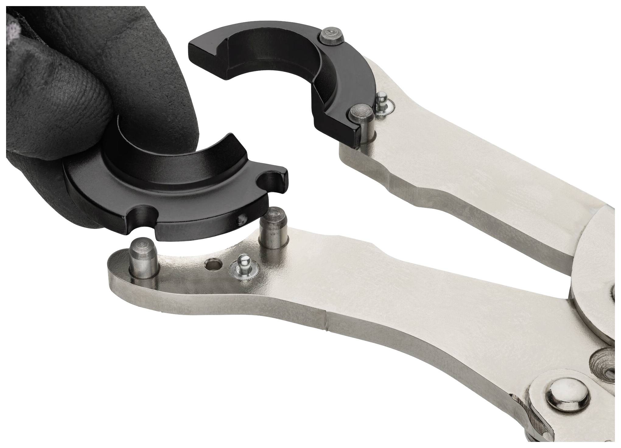 Pár kovových kleští s černým, odnímatelným příslušenstvím drží osoba v tmavé rukavici.