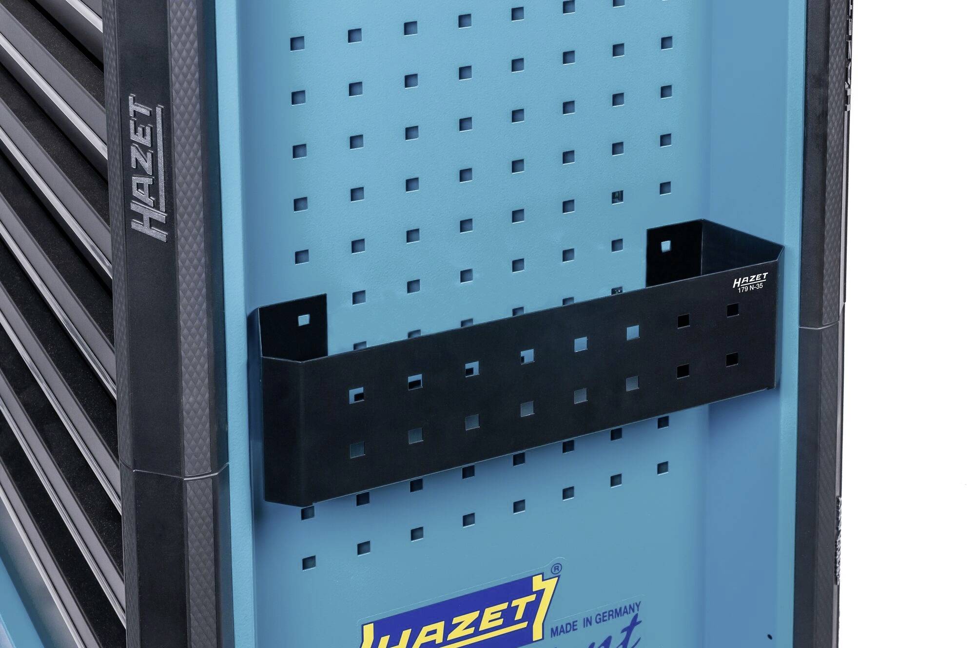 Pohled z boku na vozík na nářadí, modrý pozadí s černým držákem nástrojů, značka 'Hazet', stabilní a uspořádaný.