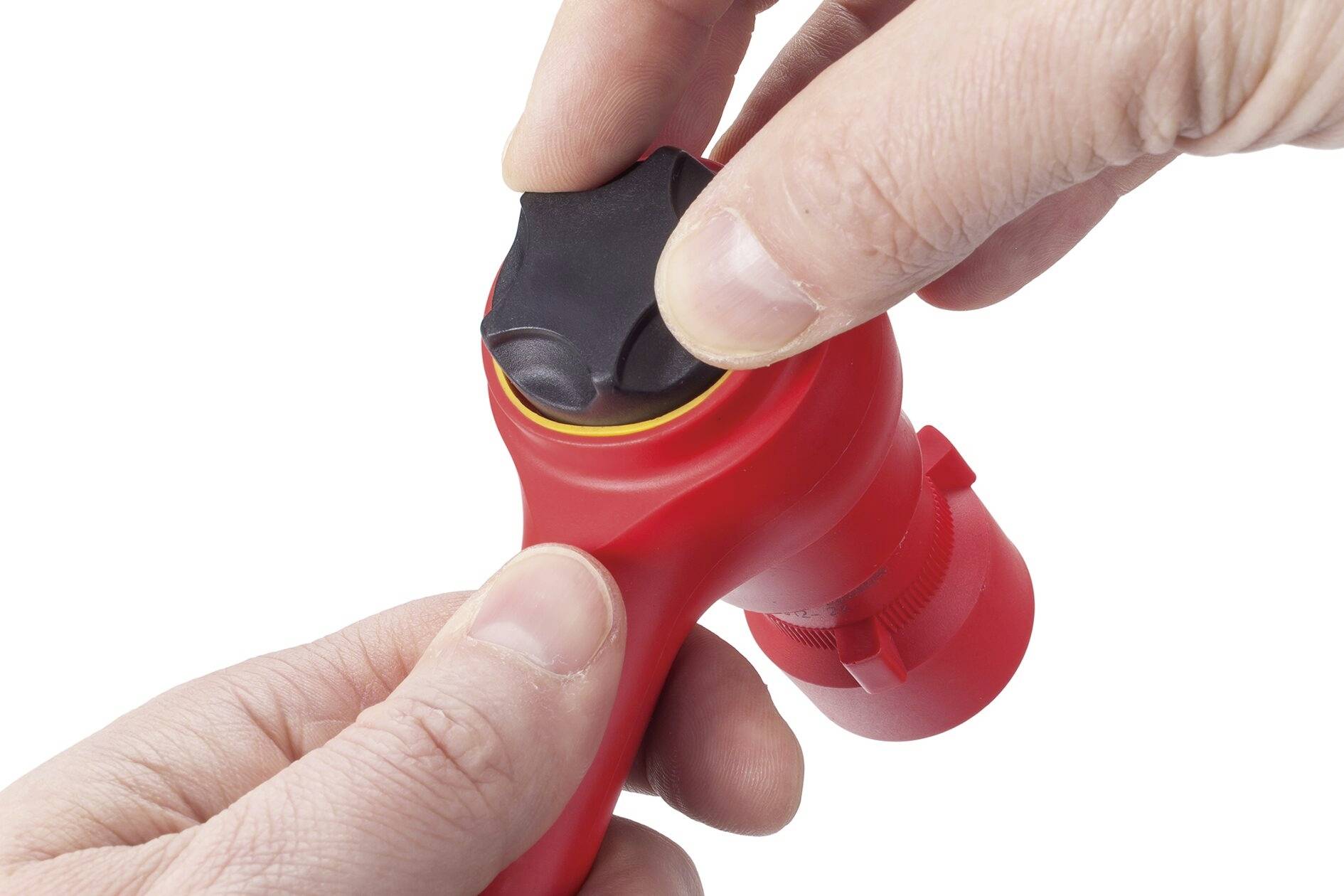 Dvě ruce ovládají červený ventil s černou otočnou hlavicí.
