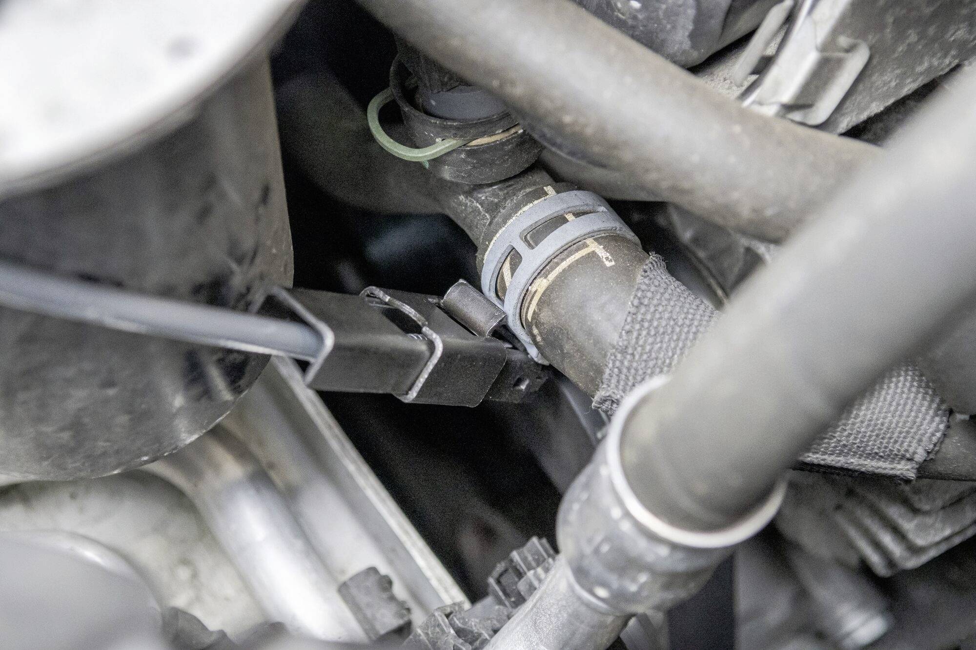 Motorový prostor vozidla s detailním pohledem na hadice a elektrické kabely propojené navzájem; znázornění mechanických detailů.