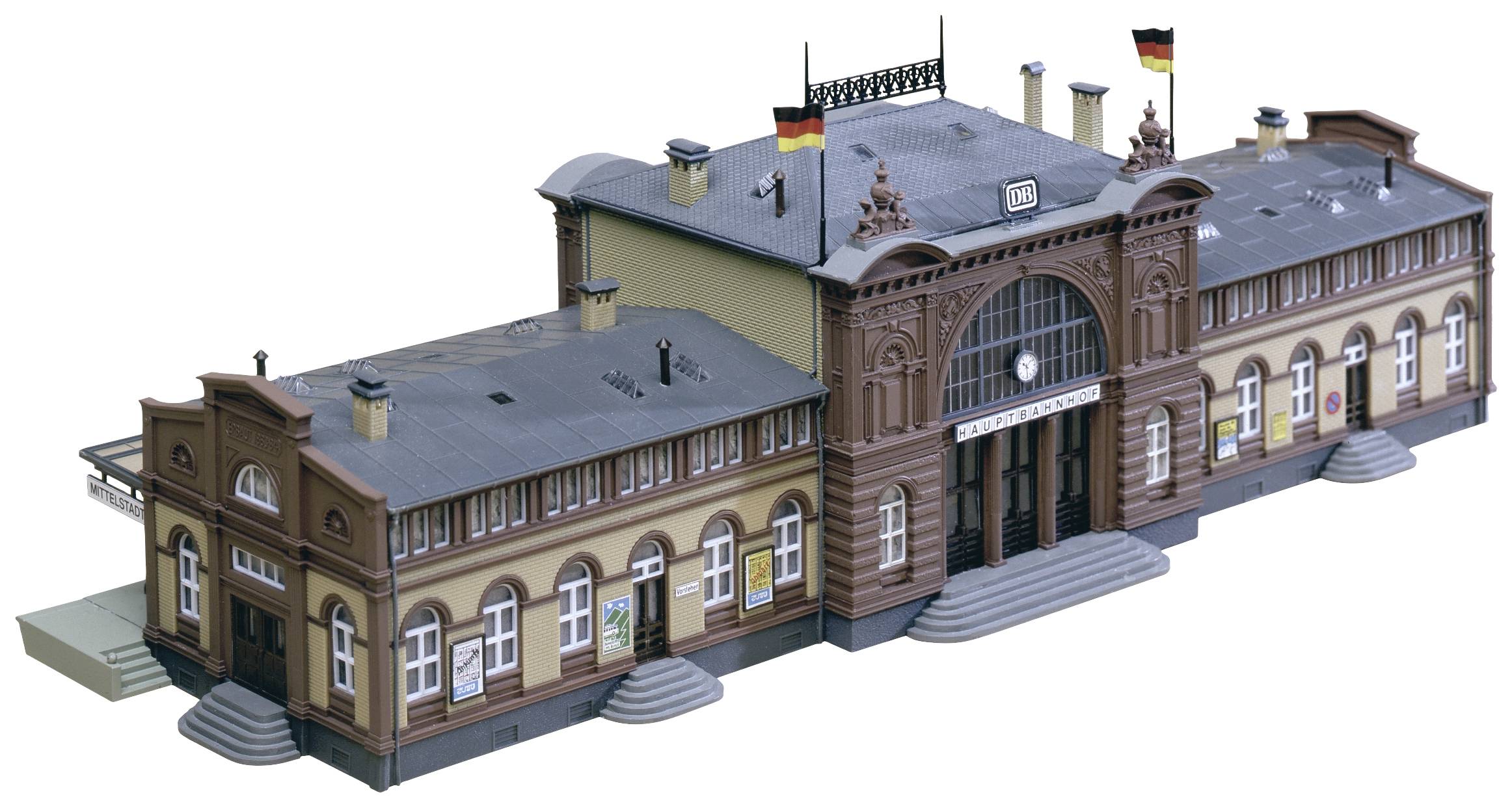 Detailní model nádražní budovy s německými vlajkami. Model zahrnuje vstupní dveře, okna a strukturovanou střechu.
