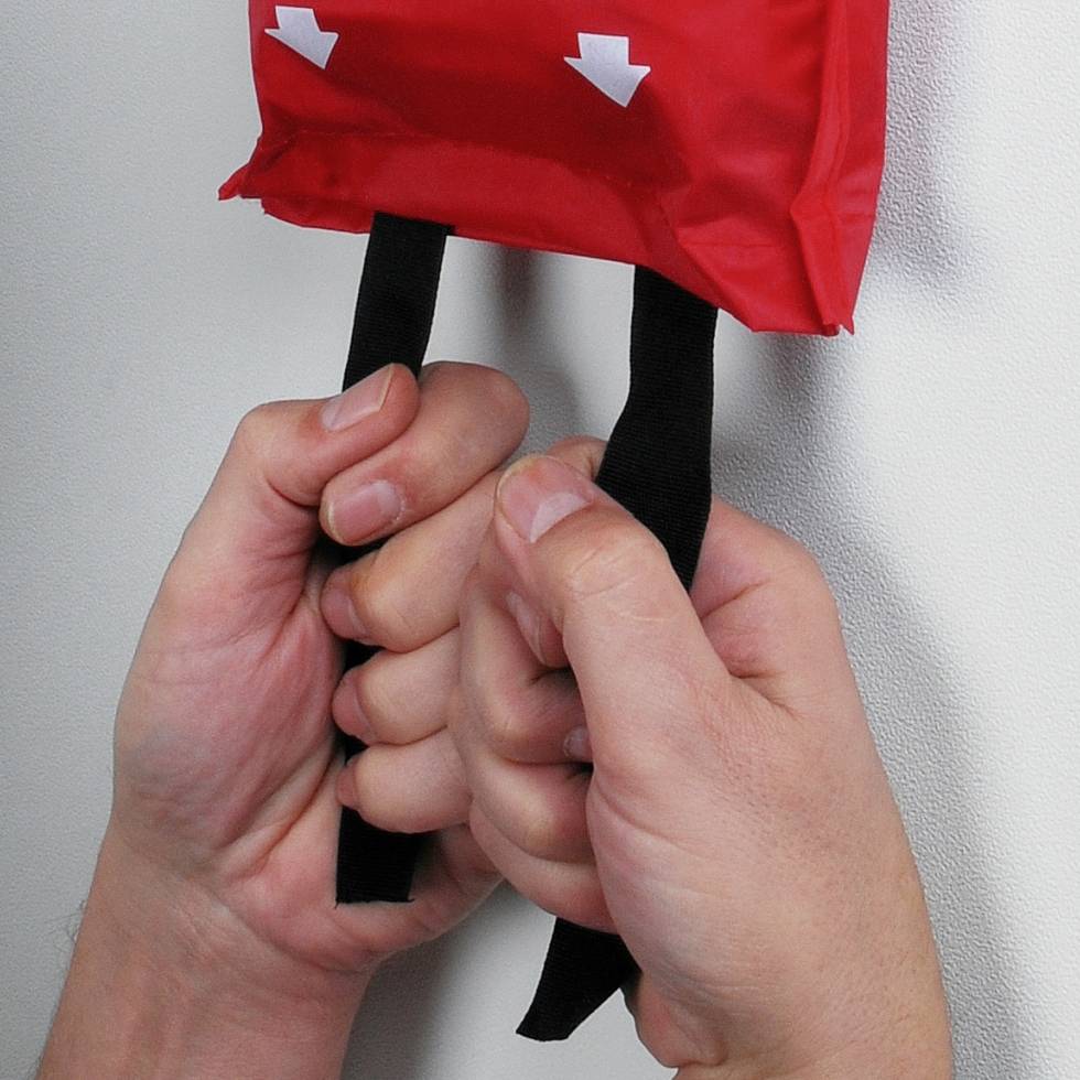 Ruce svírající s pevným stiskem červený tréninkový nástroj s šipkami směřujícími dolů symbolizují sílu a kontrolu.