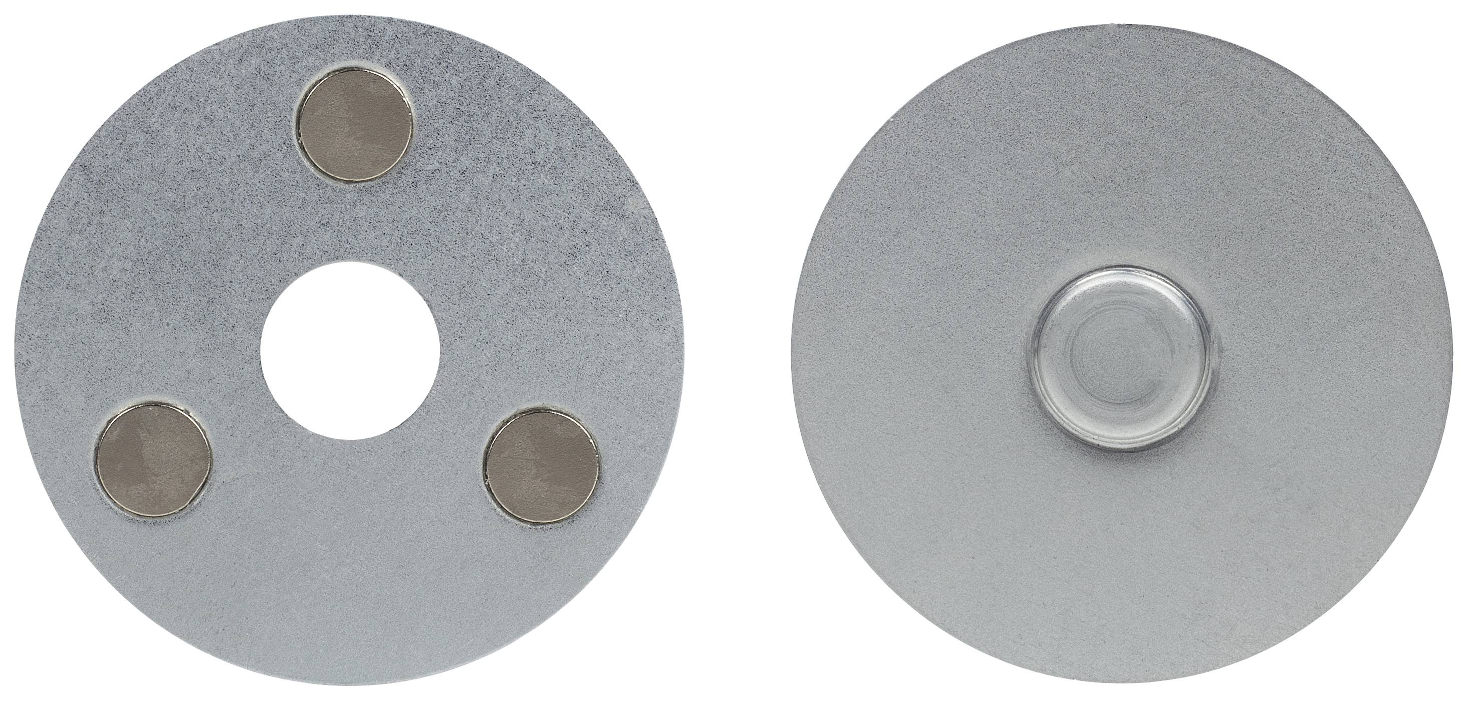 Dvě kulaté kovové desky: levá má tři magnety a centrální otvor, pravá má centrální výstupek.