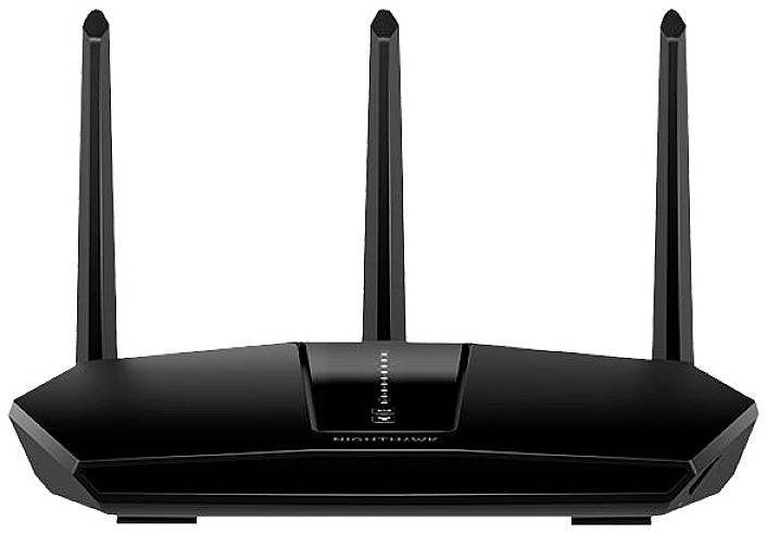 Černý Wi-Fi router se třemi anténami, umístěný centrálně na stole. Zařízení zobrazuje svítící kontrolky na přední straně.