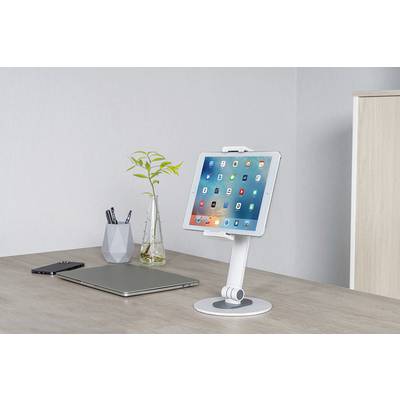 Na psacím stole stojí tablet v bílém stojánku vedle laptopem, smartphonem a vázy s větvemi.