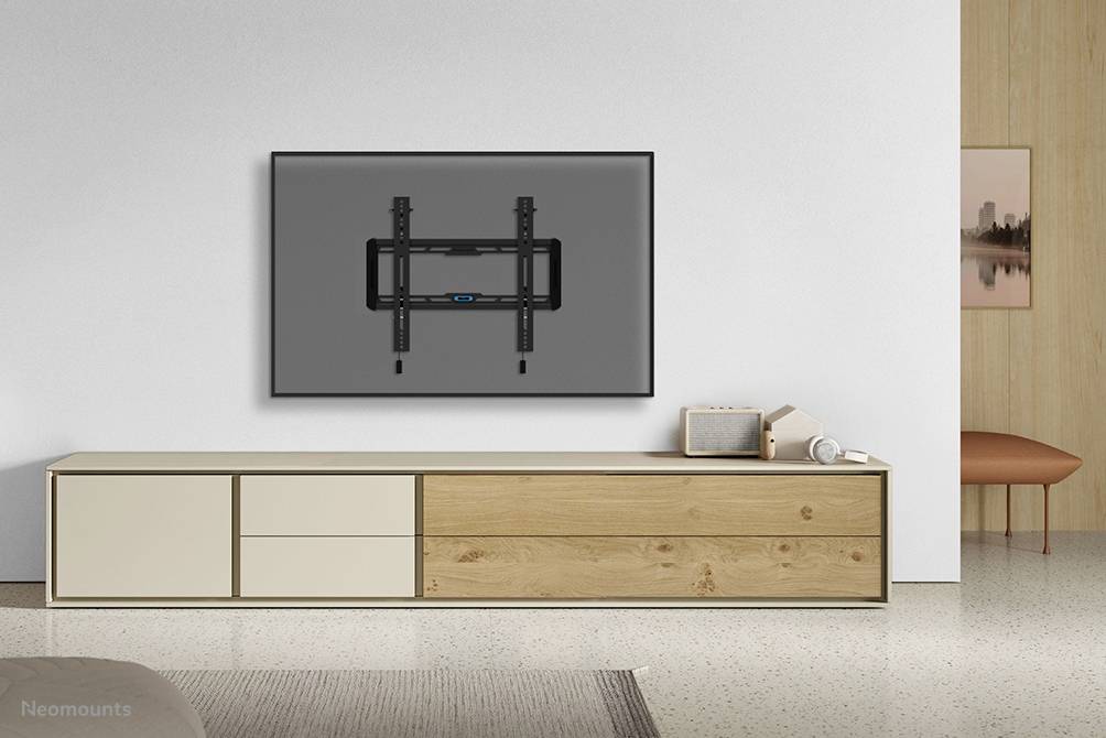 Minimalistický obývací pokoj s velkým televizorem připevněným na stěně nad moderní dřevěnou komodou.