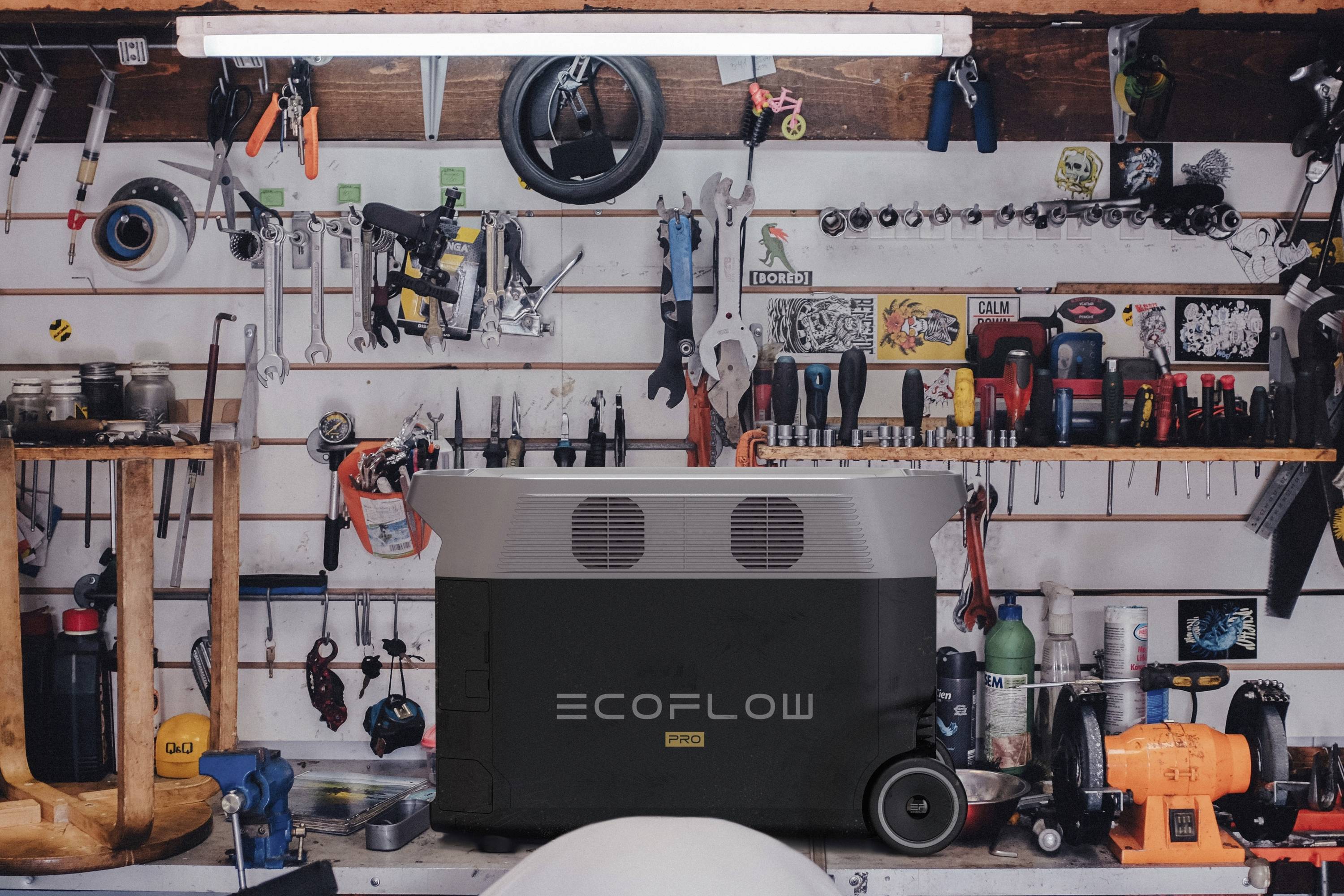 Dílní stěna s různými nástroji a velkým zařízením EcoFlow DELTA Pro umístěným na stole v popředí.