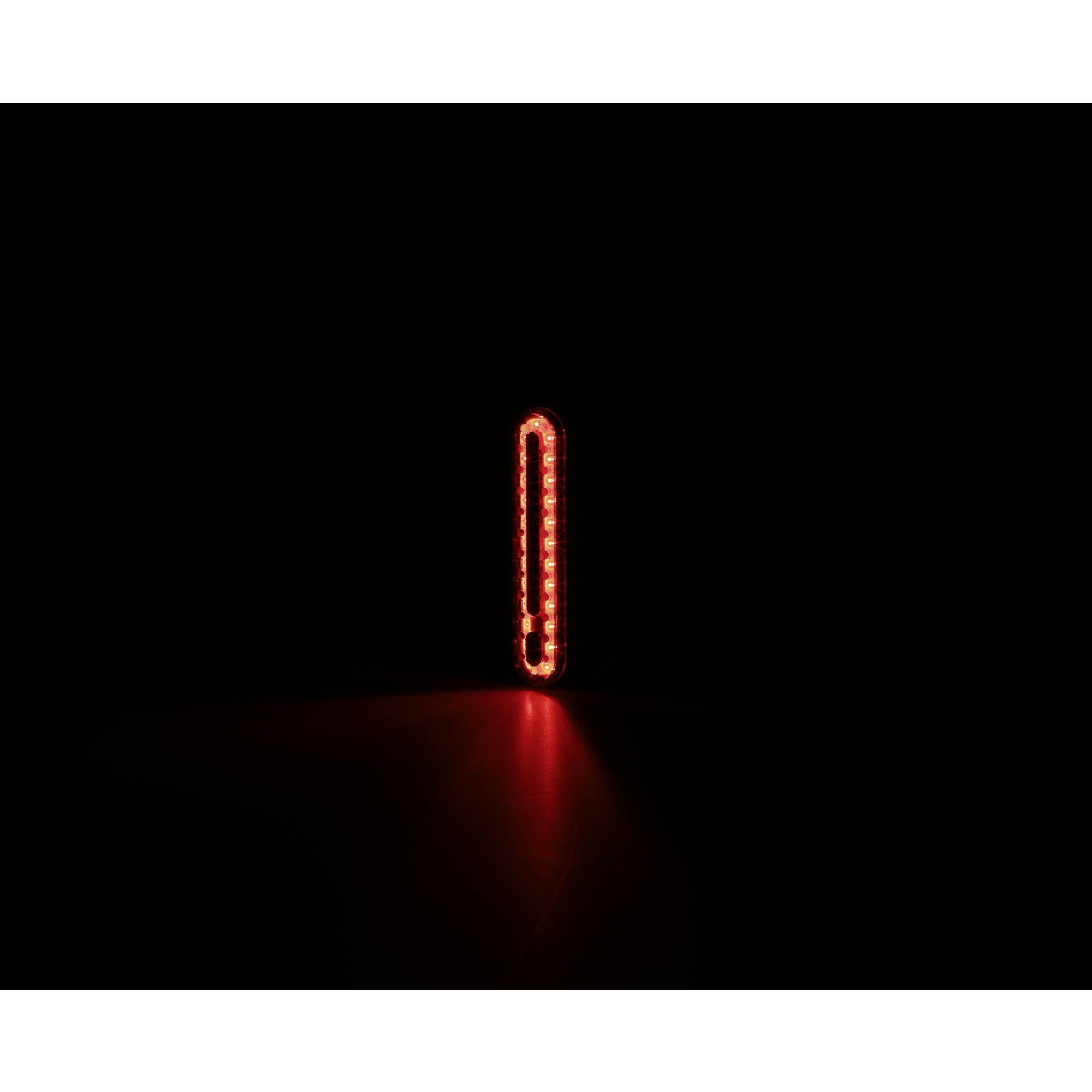 Červený vykřičník vytvořený z LED světel svítí v tmavém prostoru a pravděpodobně signalizuje varování nebo nějaký významný význam.