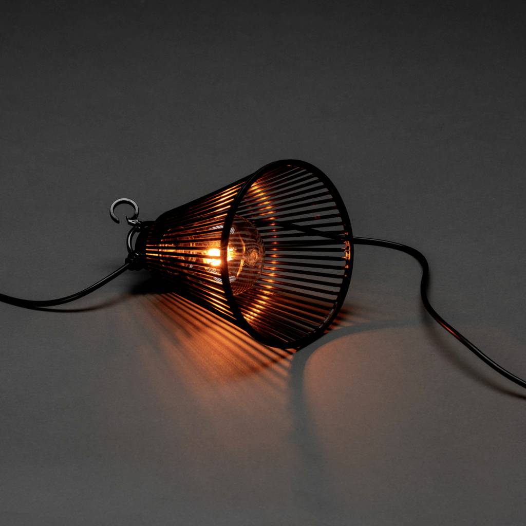 Stolní lampa v horizontální poloze s černým šikmo nasazeným stínidlem, které propouští teplé světlo žárovky.