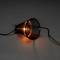 Stolní lampa v horizontální poloze s černým šikmo nasazeným stínidlem, které propouští teplé světlo žárovky.
