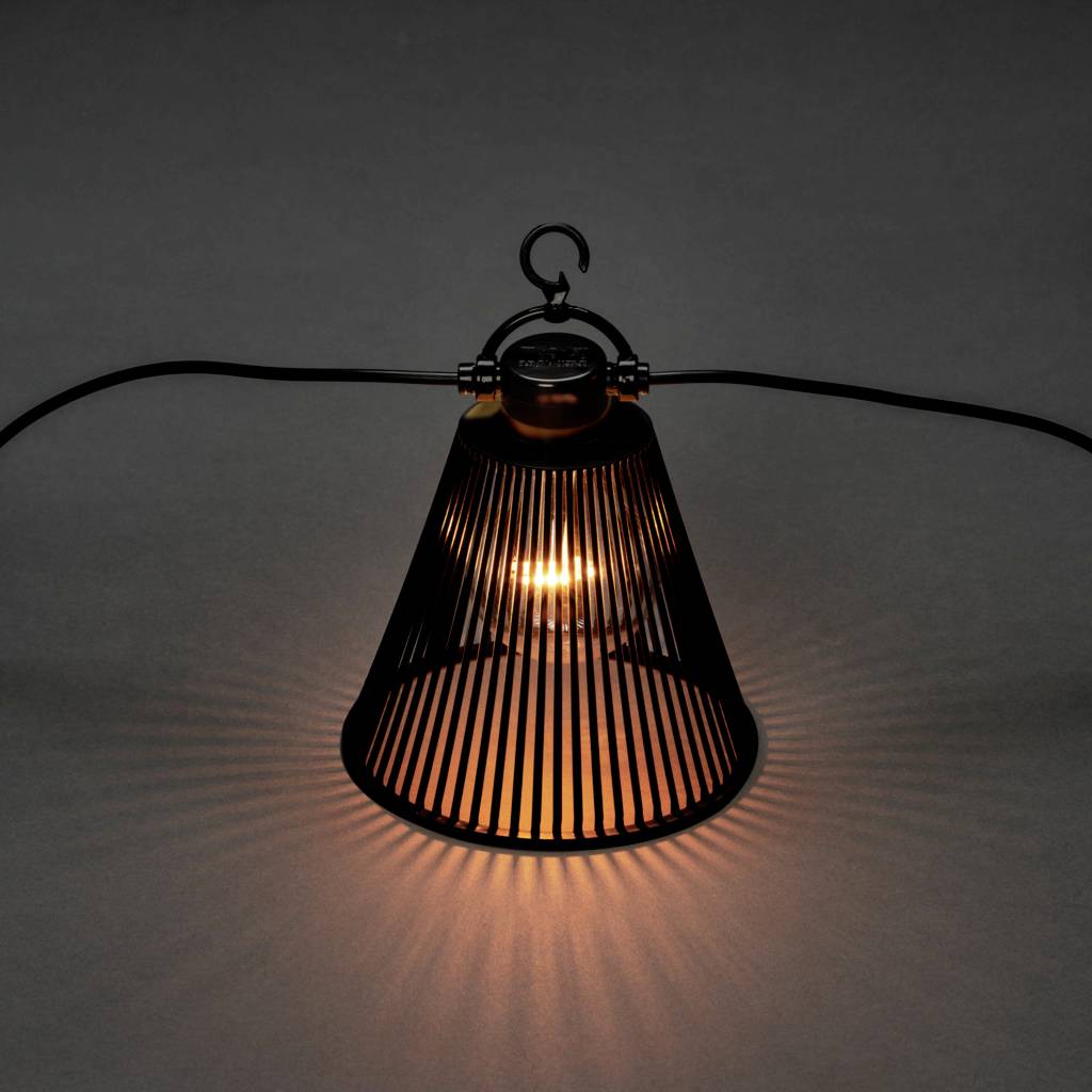 Jedna samostatná stolní lampa se svítidlem, která má černý kuželovitý stínítko a vrhá světelné vzory na šedý povrch.