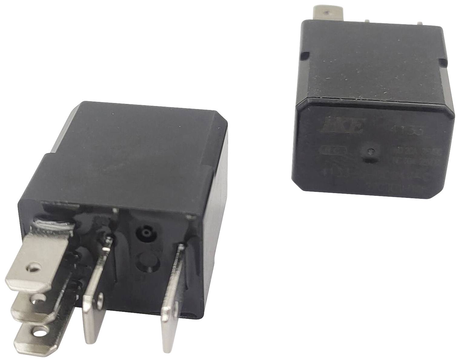 Dva černé elektronické relé s kovovými kolíky. Jedno stojí vzpřímeně, druhé leží. Ukazují připojovací místa a kontakty.