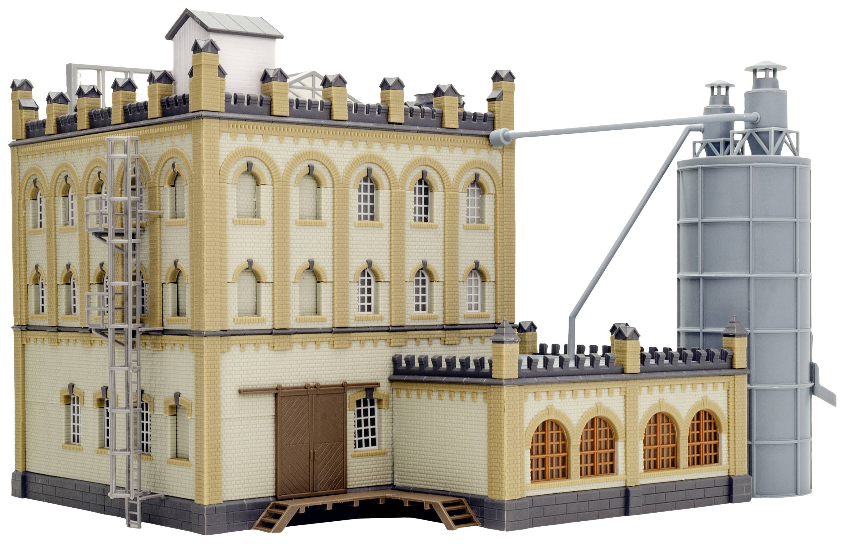 Detailní model historické tovární budovy s cihlovou strukturou, věžemi a přilehlým silem na pravé straně.