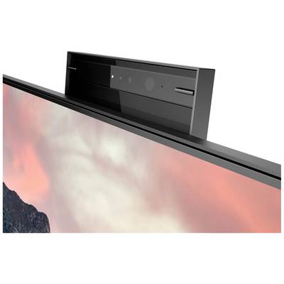 Moderní monitor s integrovanou kamerou orientovanou nahoru v horní části, před pozadím mraků a jemného světla.