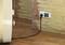 Elektrická zásuvka s měřičem spotřeby elektrické energie, který je zapojen do nástěnné zásuvky. Kabel vede k nějakému zařízení.