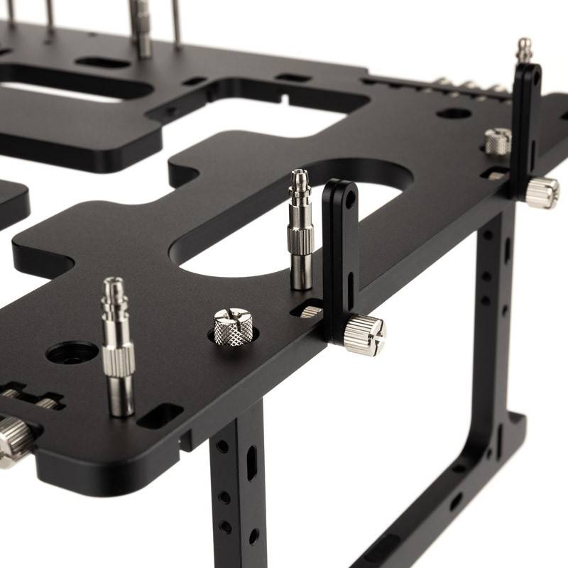 Černý kovový rám s několika vertikálními držáky a šrouby, pravděpodobně určený pro technickou nebo mechanickou montáž.