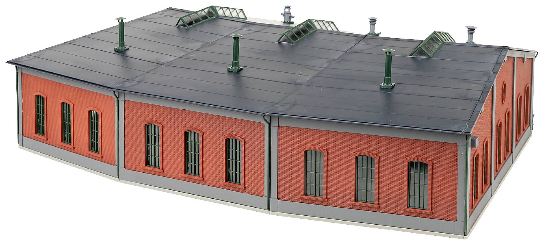Velký model cihlově červené budovy s šedou střechou, několika komíny a střešními okny.